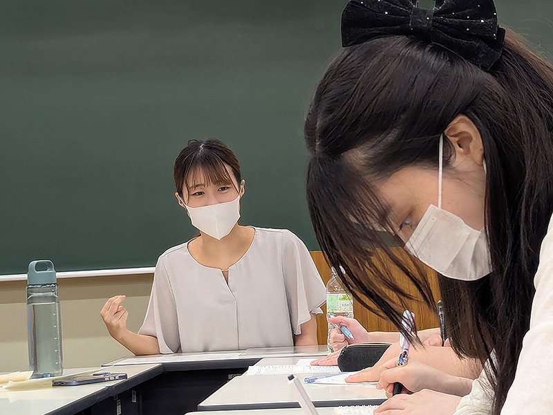 真剣にメモを取る学生と説明をする看護師